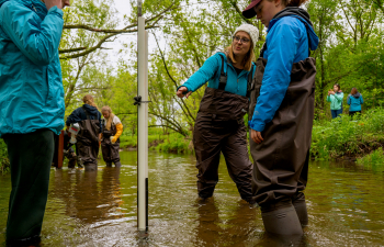 A group of people stand in the Kinnickinnic River in waders conducting research