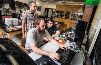 a student and faculty member look at a computer screen