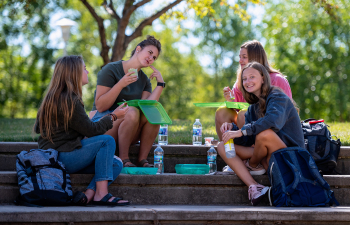 Four female students enjoy lunch outside on the UC lawn