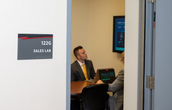 a classroom with a sign outside the door that reads "Sales Lab"
