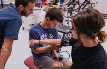 Two students take the blood pressure of another student during a health lab